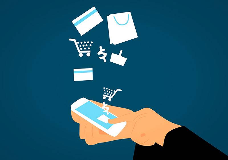 ecommerce An individual holding a phone with various icons popping out of it including a shopping cart and credit card illustrating the role ecommerce solutions play in our daily lives.