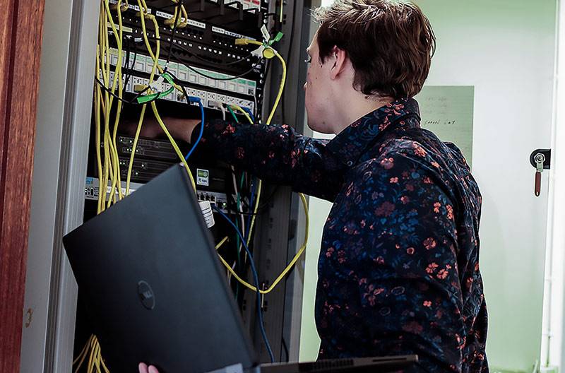 networkadministration A man reaching into a server rack demonstrating the skill of network administration