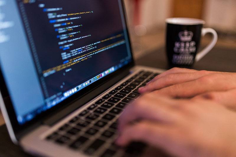 websitedesign A man typing code on his keyboard, illustrating website design and development